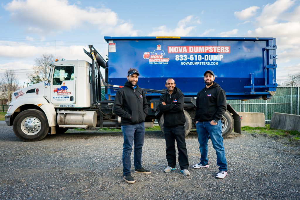 nova dumpster crew standing in front of their blue dump truck
